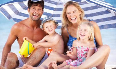 Rodina pod slunečníkem na pláži / Foto: Depositphotos